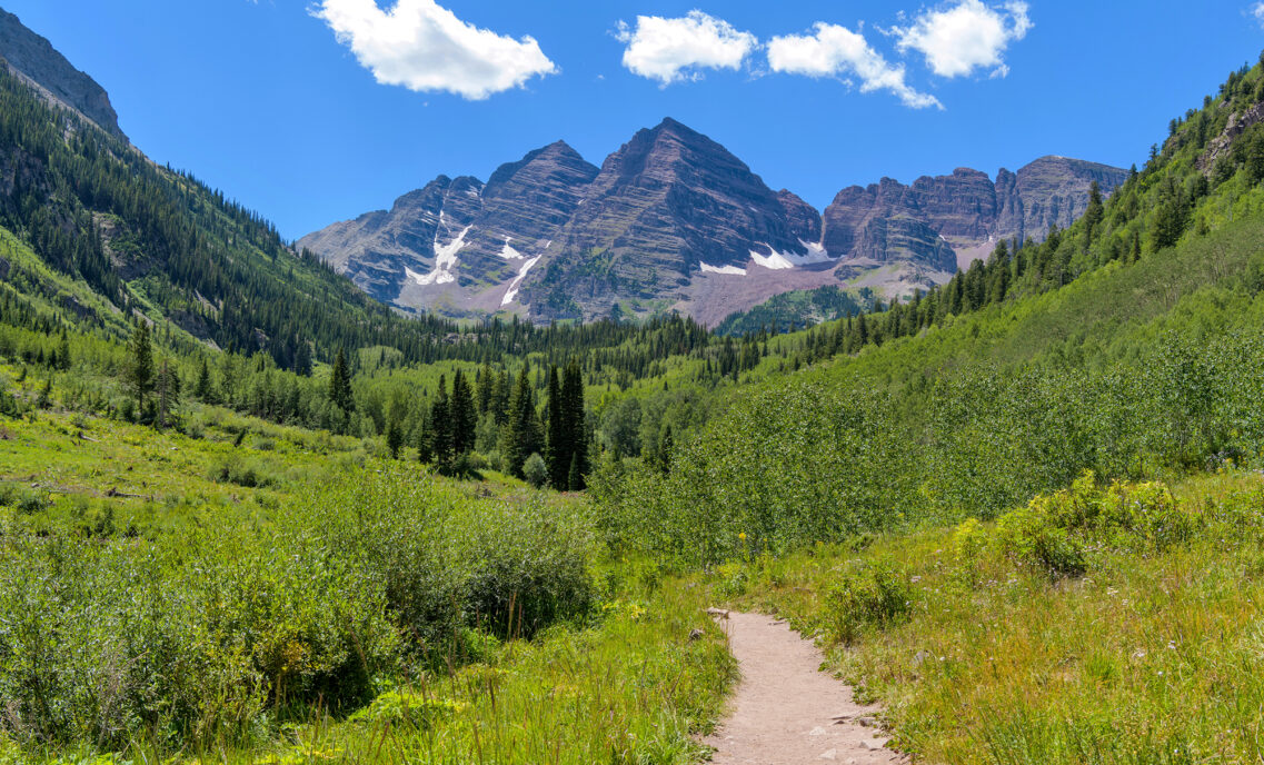 A scenic photo of Aspen featuring a grassy path and a mountain in the background
