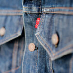 No.1 CITI A close up of the front pockets of a Levi's® denim jacket featuring a red Levi's® tab