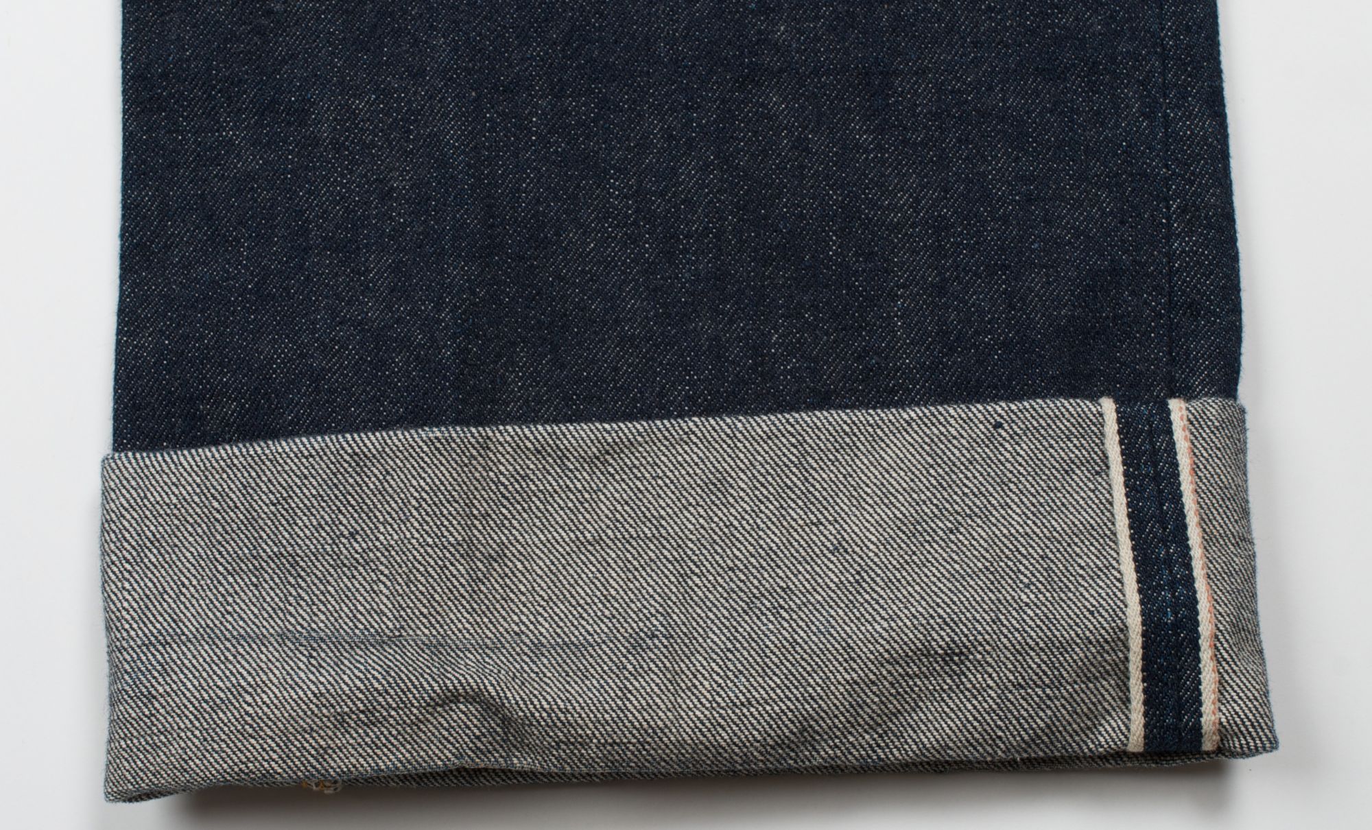 the bottom rolled up cuff of a pair of denim jeans
