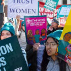 People gather holding signs advocating for reproductive rights and abortion access.