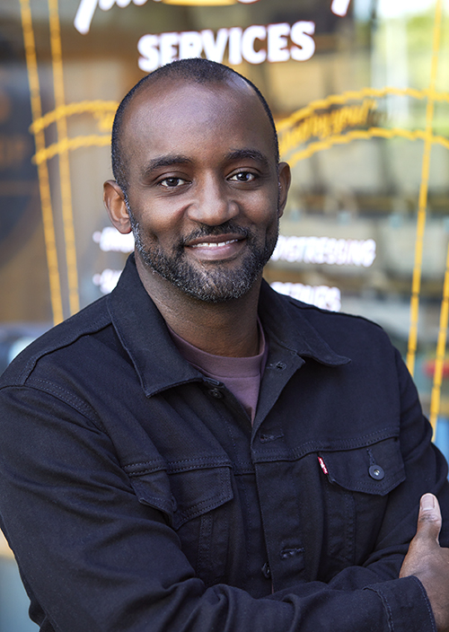 A portrait of LS&Co. Chief Marketing Officer Kenny Mitchell smiling and wearing a black Levi's® button-up shirt.