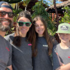 Orla Hollub, VP, global head of finance and strategy at Dockers®, smiles with her husband and two children. They are all wearing matching grey long sleeve shirts with the word "build" on the right pocket.
