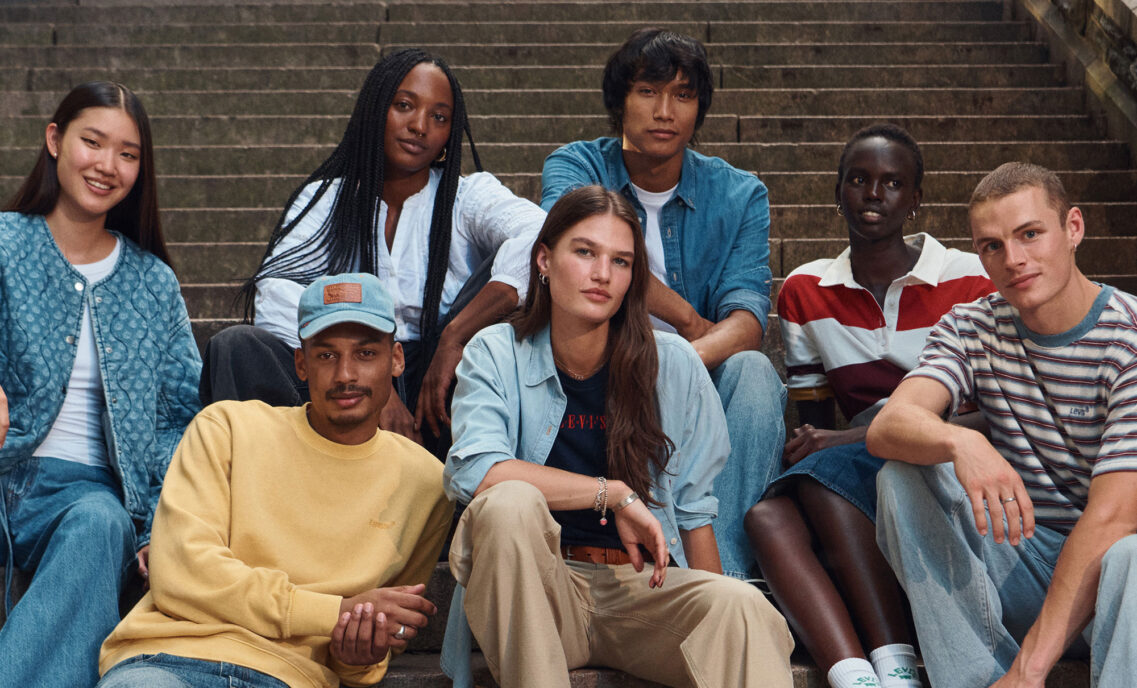 A group of seven individuals dressed in Levi's® outfits sit on outdoor steps