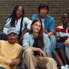 A group of seven individuals dressed in Levi's® outfits sit on outdoor steps