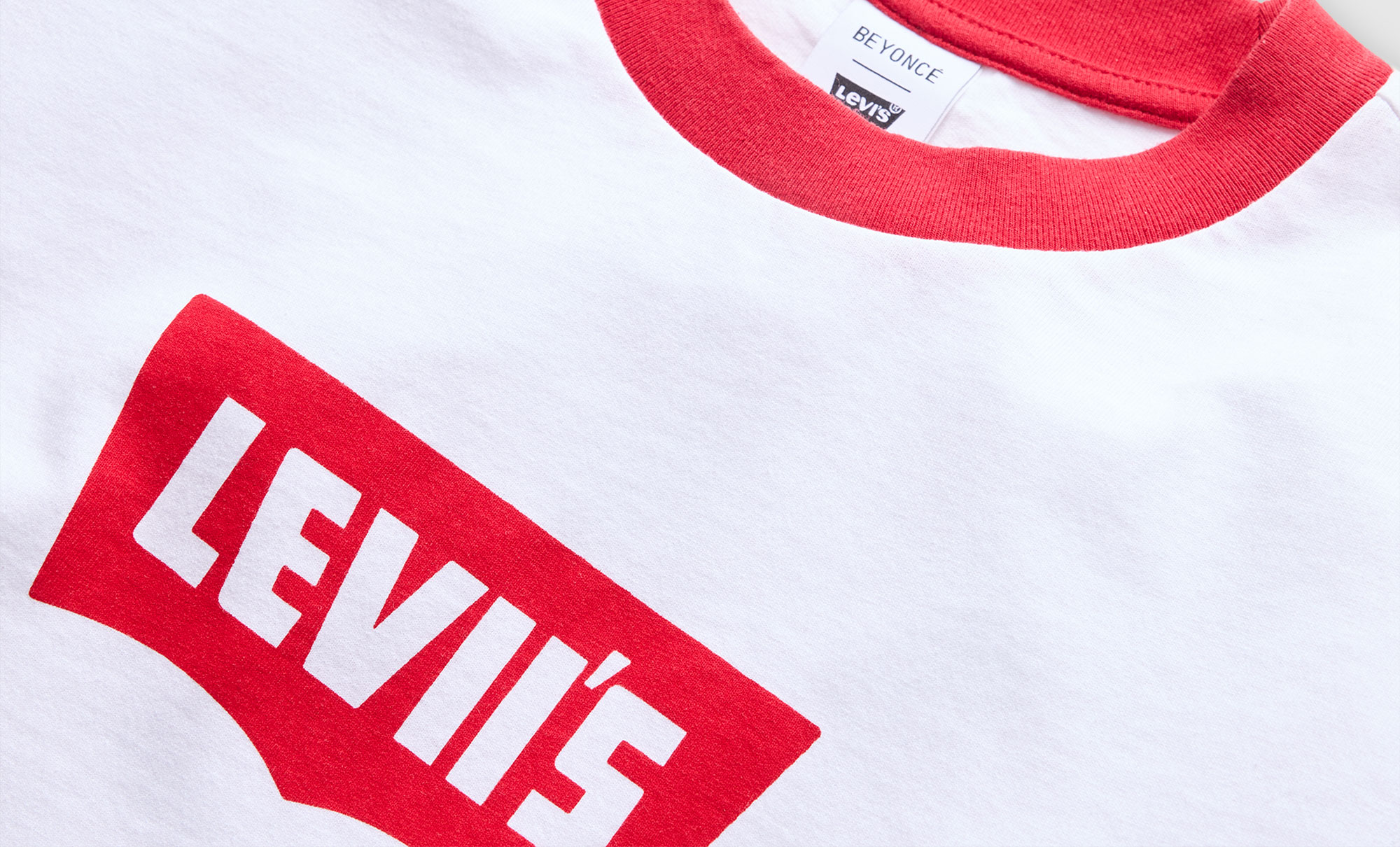 Close up of a white ringer tee with a red collar and a red Levi's® batwing logo graphic reading "Levii's"