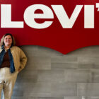 Levi's manager Kelly Perl smiles and stands in front of a wall featuring a large red Levi's batwing logo.