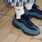 A pair of feet wearing a Levi's® x Nike Air Max 95 in blue denim with white Nike socks.