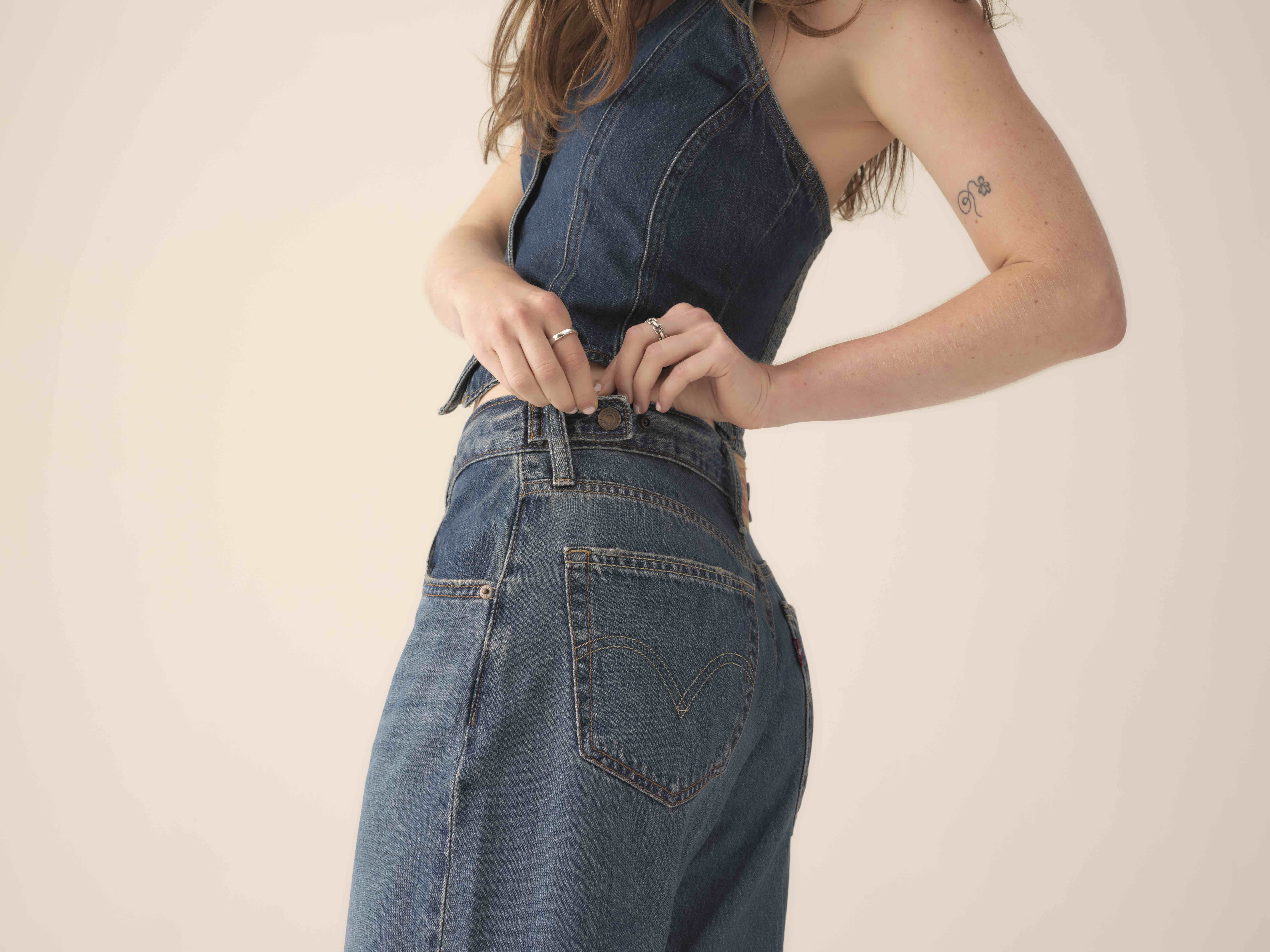 A person adjust the waistband on their Levi's® cinch baggy jeans