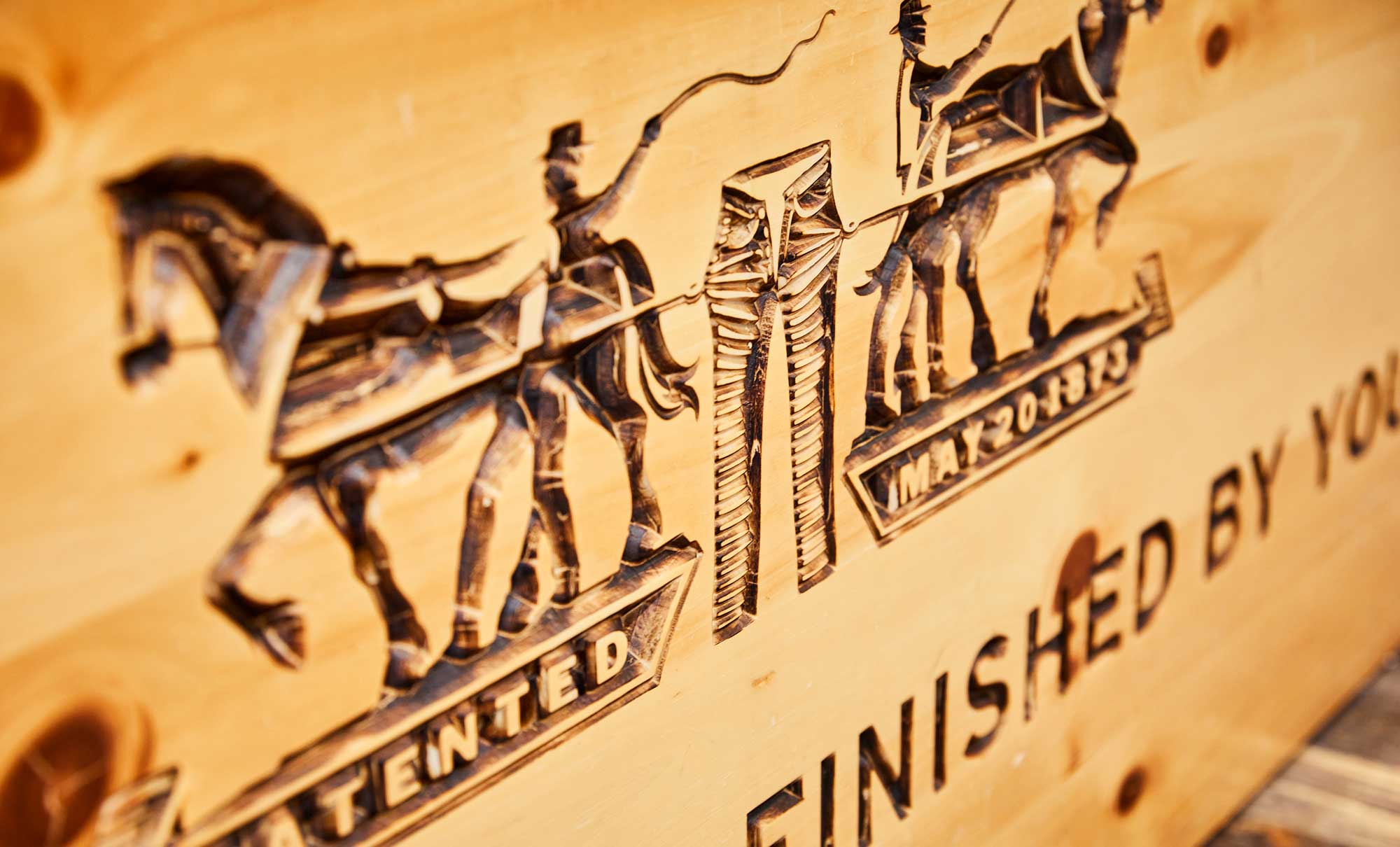 A wood carving of the Levi's® Two-Horse pull logo