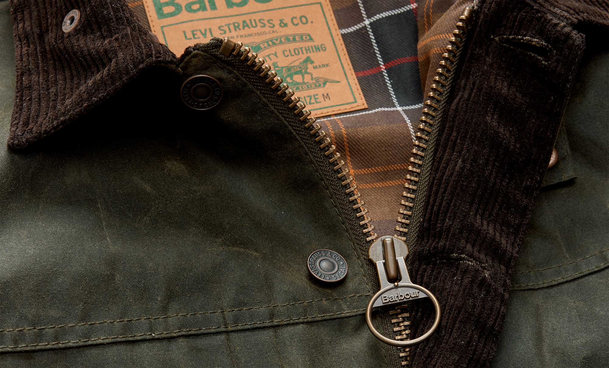 A close up image of the Levi’s® x Barbour Spey Wax Jacket, which reimagines Barbour’s classic silhouette in tobacco wax with brown cord collar, featuring pocket flaps shaped like Levi’s® iconic arcuate, trucker-style cuffs and waistband, and a back-cinch characteristic of Levi’s® archival denim. With moleskin pocket lining and co-branded elements throughout, the piece bridges outdoor functionality with authentic Western workwear DNA.