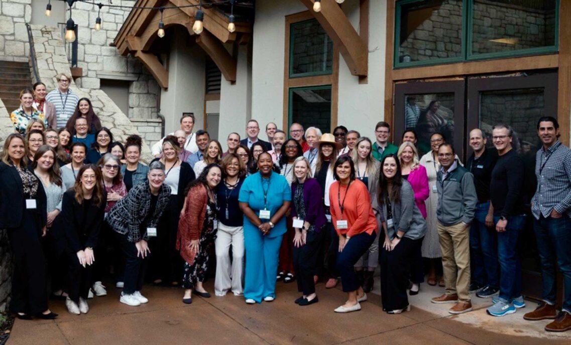 Employees from Levi Strauss & Co.'s Red Tab Foundation, the Epic Promise Fund at Vail Resorts and leaders from other companies including Home Depot, HCA Healthcare, Chick-fil-a, Giving Kitchen adn Walmart smile for a group photo in front of a Vail Resorts building facade.