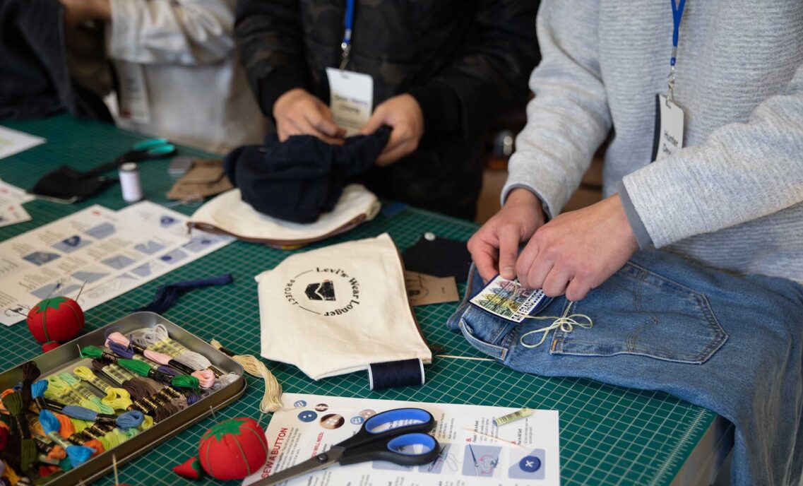 The hands of two high schoolers are seen completing sewing projects as part of the Levi's® Wear Longer Project workshop at the Levi Strauss & Co. Eureka Innovation Lab