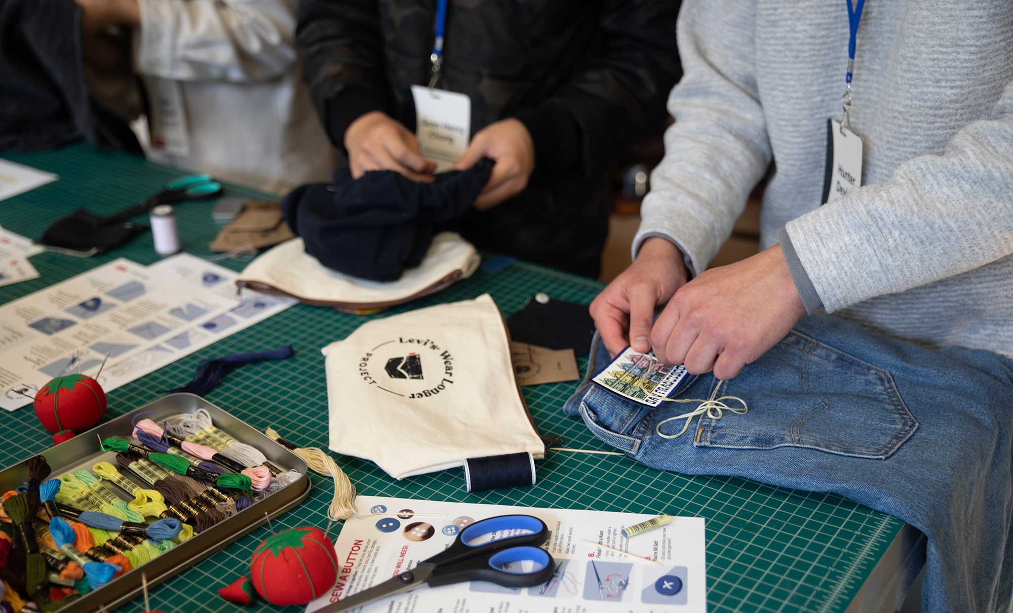 The hands of two high schoolers are seen completing sewing projects as part of the Levi's® Wear Longer Project workshop at the Levi Strauss & Co. Eureka Innovation Lab