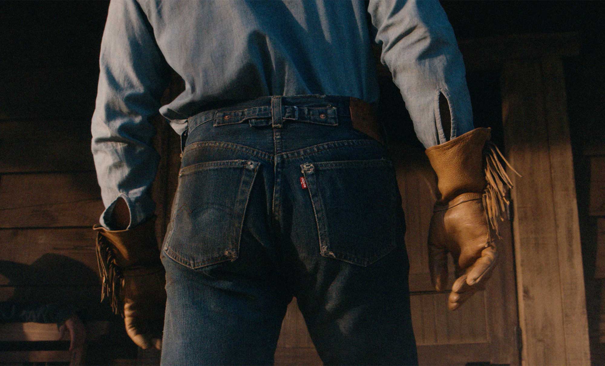 The backside of a person wearing Levi's® dark was denim jeans with a long sleeve light blue shirt